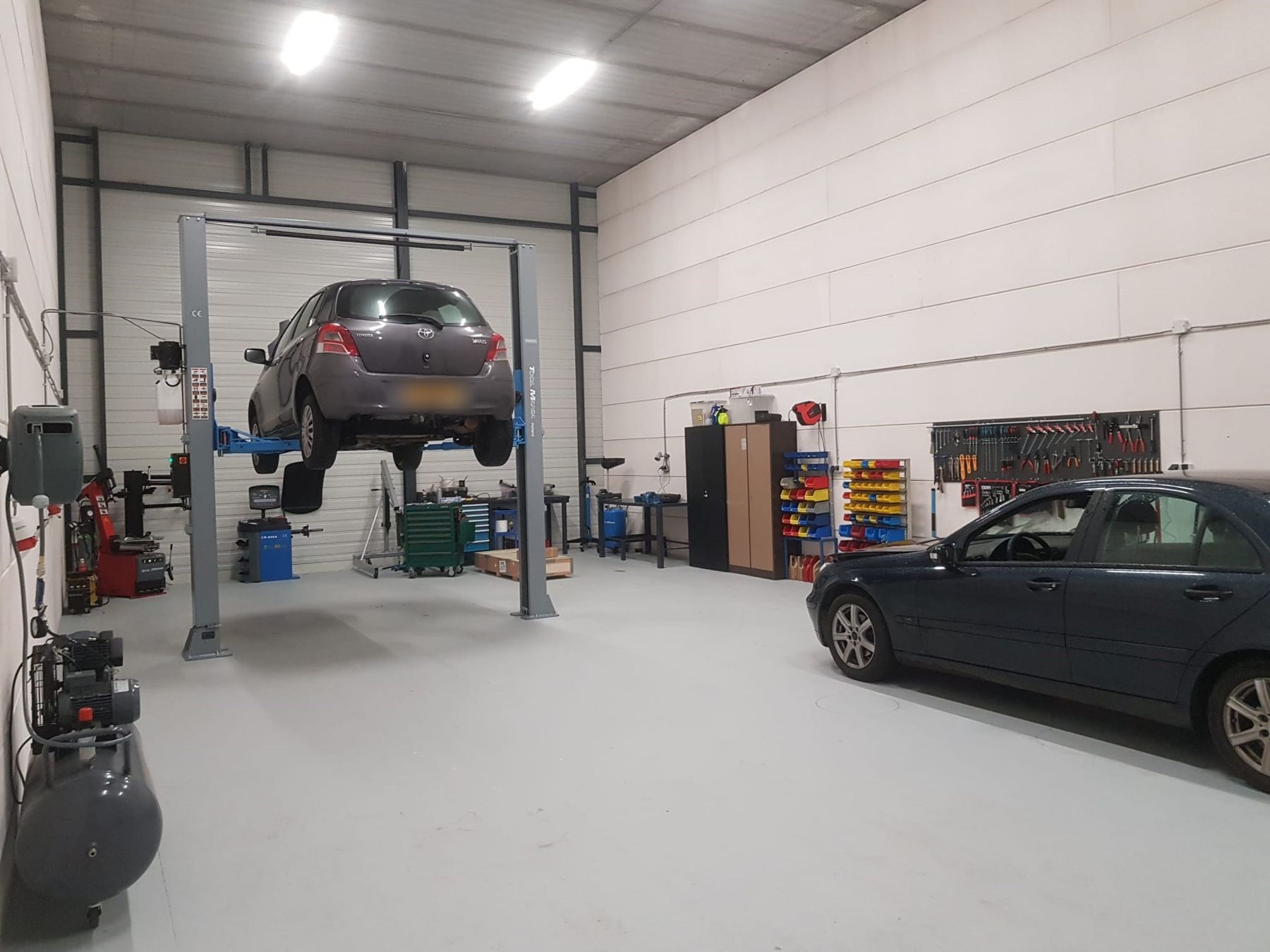 De werkplaats van GK Cars AutoGarage met een auto op de brug