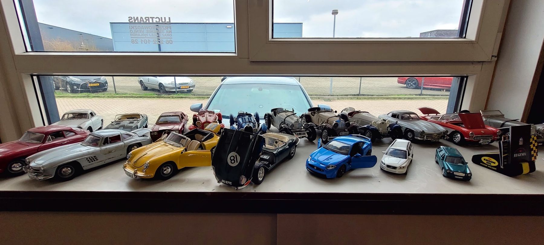 Een verzameling modelauto’s op de vensterbank van de werkplaats