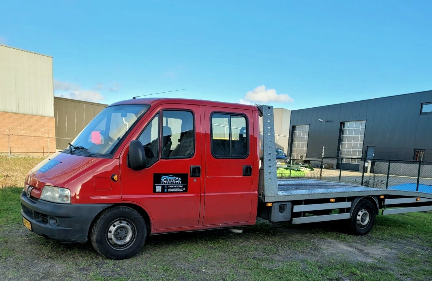 De rode oprijwagen van GK Cars bij de bedrijfsunits in Sevenum