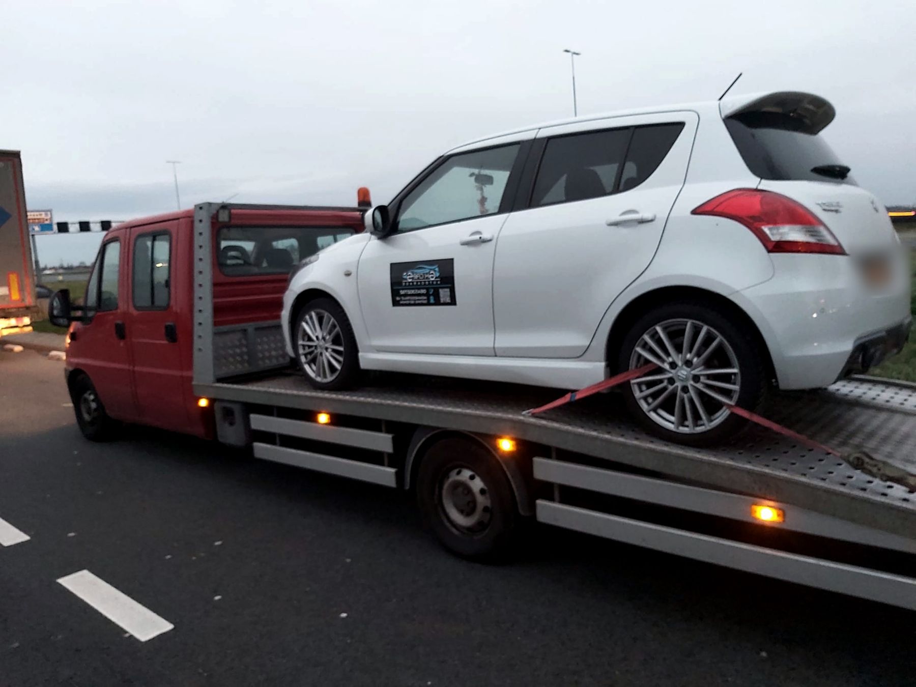 De rode oprijwagen van GK Cars laadt een witte auto